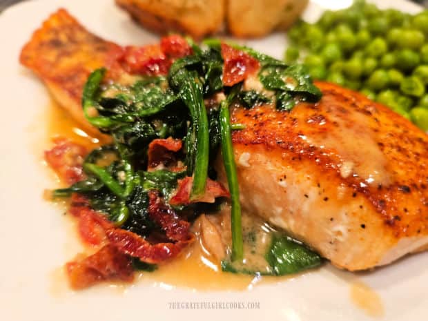 A serving of salmon in spinach cream sauce, served on a white plate.