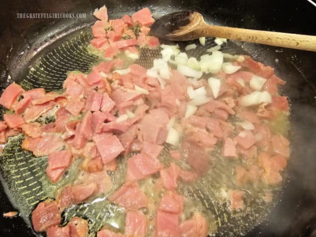 Chopped onions are cooked with small ham pieces in melted butter.