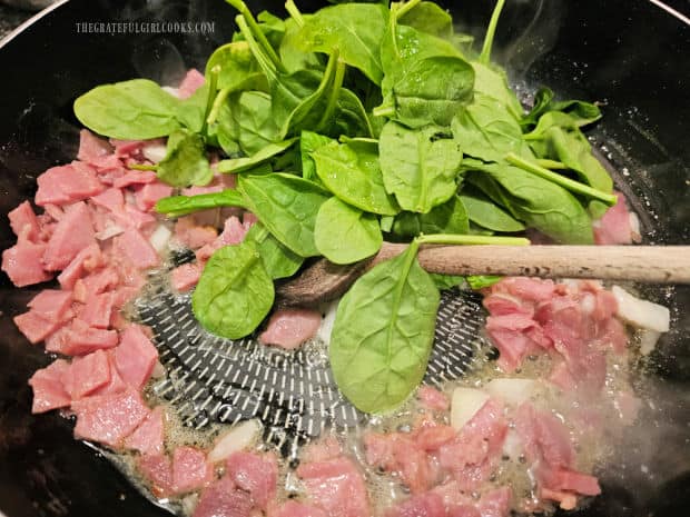 Baby spinach leaves are added to the skillet with ham, butte and onions.