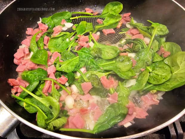 The spinach begins to wilt in the heat of the skillet.