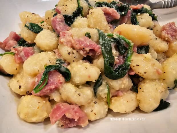 A close up of the Ham and Parmesan Gnocchi with spinach, on a white plate.