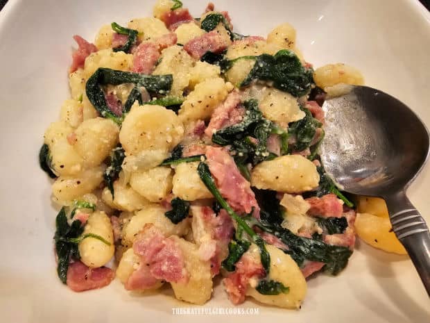 The ham and Parmesan gnocchi is served hot, in a white bowl.