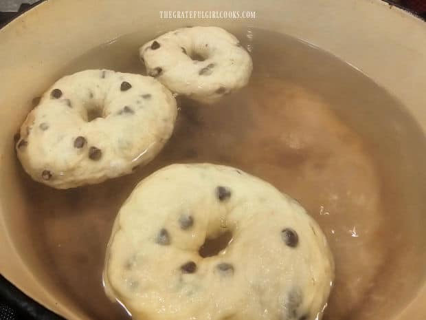 Chocolate chip bagels are boiled, 3 at a time, before baking.