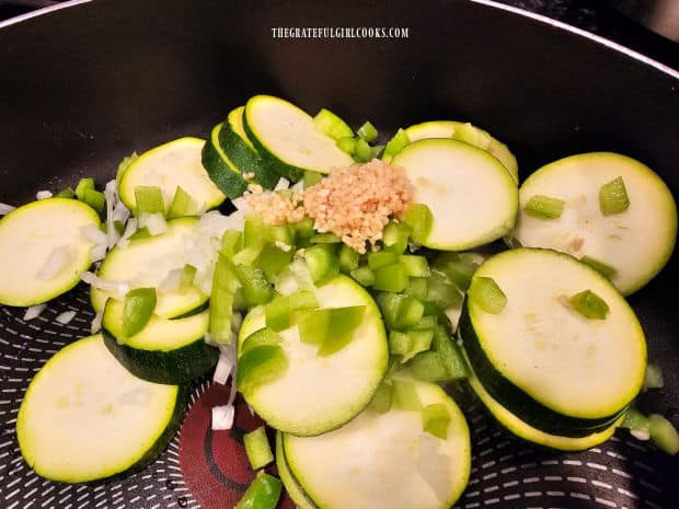 Zucchini slices, onions, garlic and green peppers are cooked in olive oil.