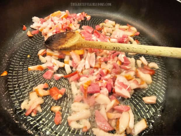 Small pieces of bacon are cooked until very crispy in a large skillet.