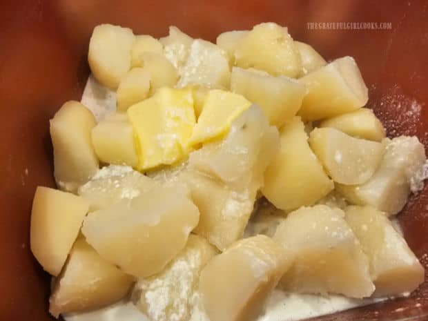 Butter and whipping cream are added to very hot, drained potatoes in pan.