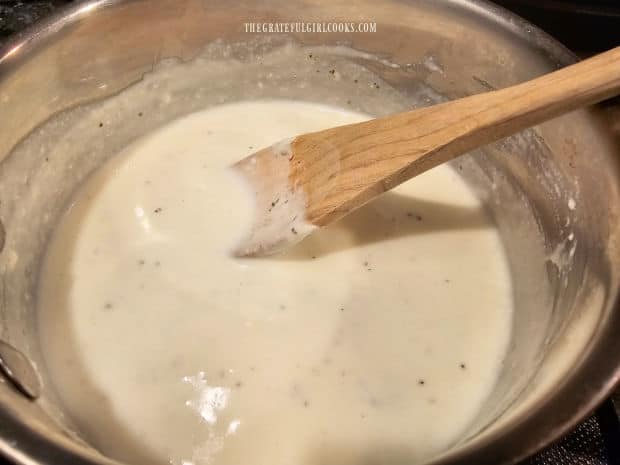 Seasoned cream sauce cooks in saucepan until smooth and heated through.