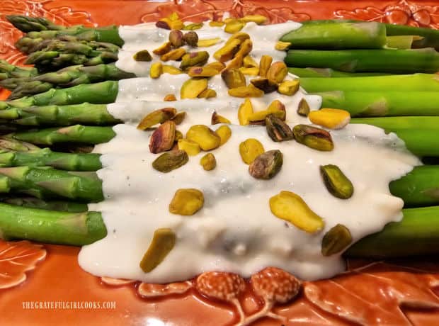 Hot cream sauce and chopped pistachios are added to garnish the asparagus.
