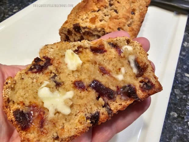 A slice of warm banana apricot date bread, with melted butter on top.