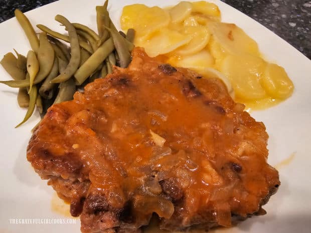 Simple savory pork chops served on a plate with green beans and potatoes.