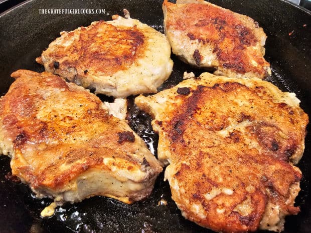 After browning one side, pork chops are turned over to brown the other side.