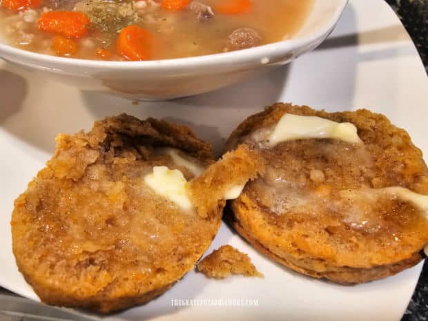 Cut in half, topped with butter, sweet potato biscuits are served with soup.