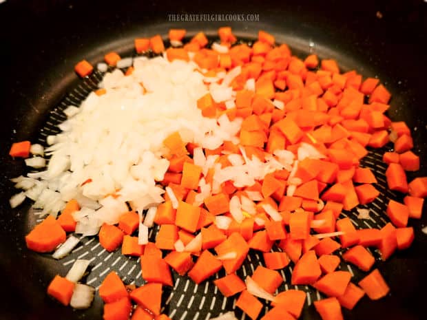 Diced onions and carrots cook in oil in a large skillet.