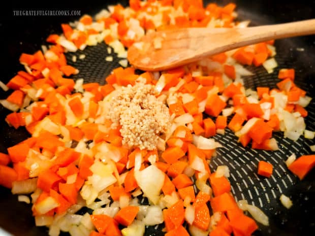 Minced garlic is stirred into the cooked carrots and onions.