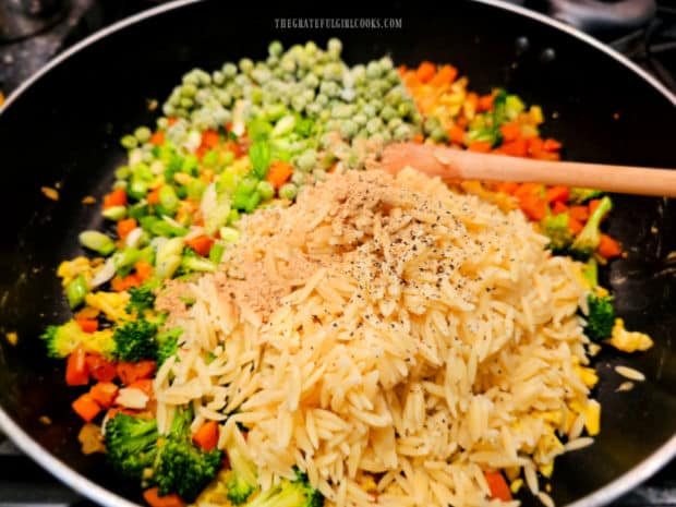 Peas, orzo, spices, green onions, soy sauce and spices are added to skillet.