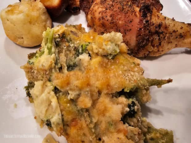 A serving of the veggie casserole with chicken and a dinner roll on the side.
