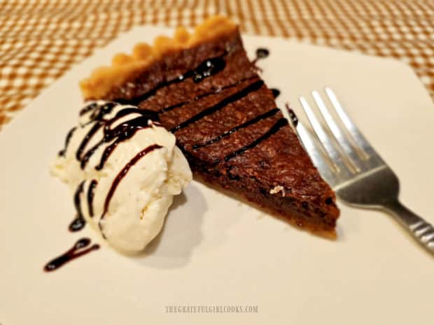 Slice of chocolate chess tart, served with ice cream and chocolate syrup.