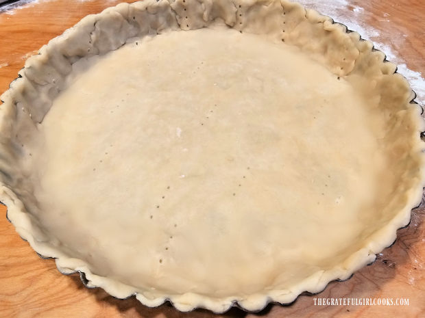 A tart crust is placed in a tart pan, and is ready for filling.