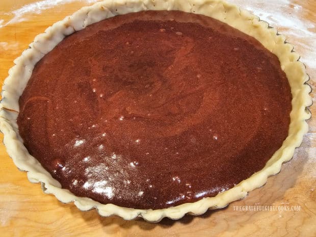 The chocolate chess tart filling is poured into the tart shell in pan.