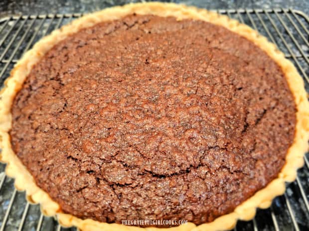 A chocolate chess tart cools on a wire rack after baking.