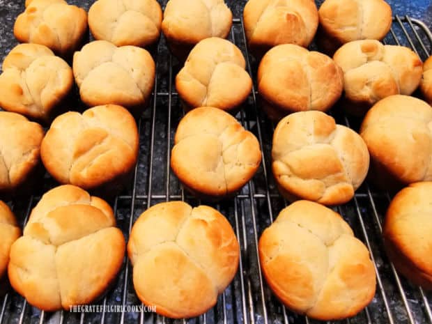 Golden brown rolls on a wire rack after baking.