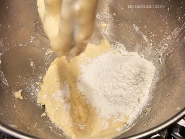 Flour is added to the dough a small amount at a time.