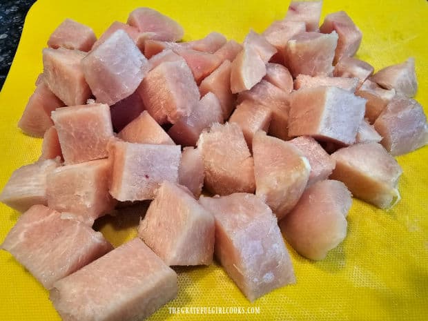 Boneless skinless chicken breast is patted dry, then cut into bite-sized cubes.