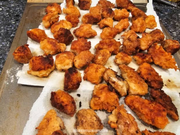 Fried chicken bites drain on paper towels after they're done cooking.