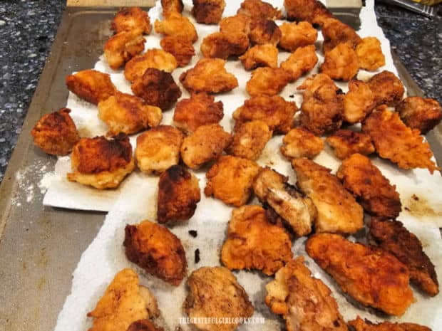 Fried chicken bites drain on paper towels after they're done cooking.