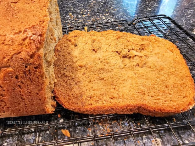 A slice of oatmeal molasses bread, cut and resting on a wire rack.