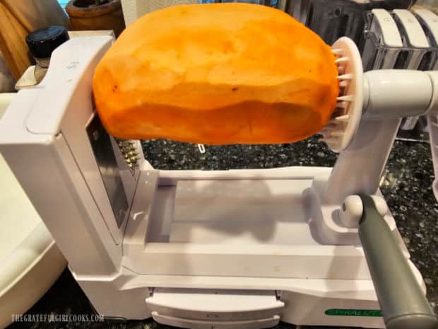 A sweet potato, positioned in place on a spiralizer machine.