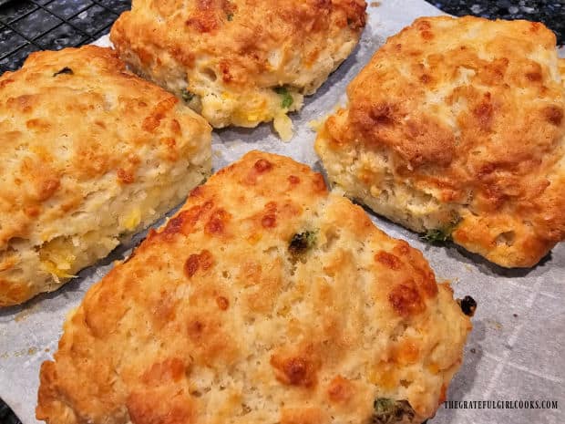 Biscuits cool on parchment paper on a wire rack after cooking.