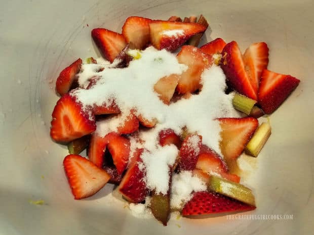 Strawberries and rhubarb slices in a large bowl with sugar, lemon juice, etc.