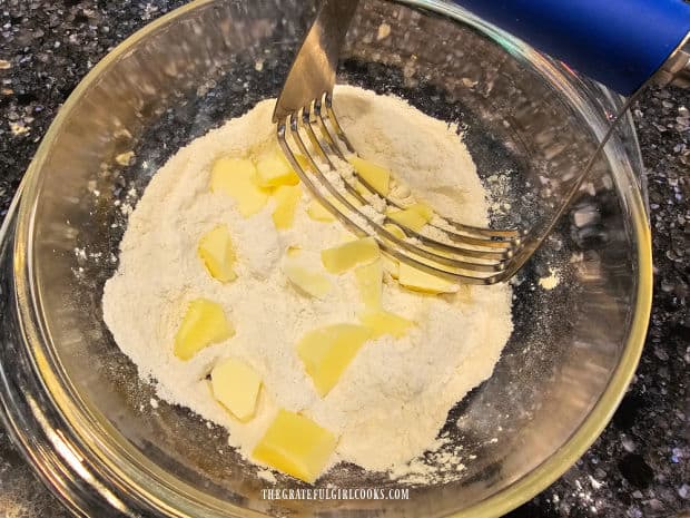 Cold butter chunks are cut into the dry ingredients for the cobbler topping.