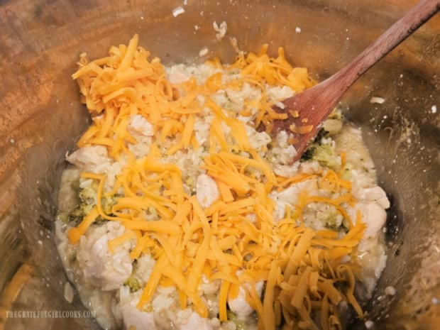 Grated cheddar cheese is stirred into the chicken mixture.