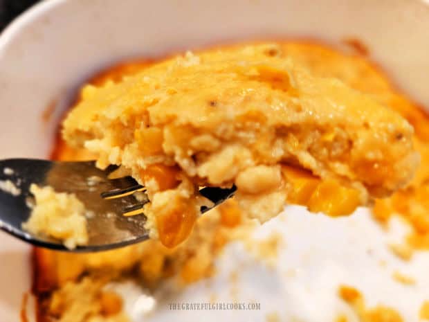 A fork, holding a bite of the easy corn soufflé, ready to be eaten.