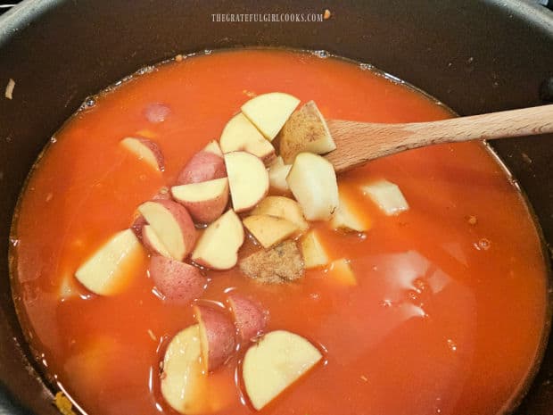 Water and bite-sized potatoes are added to the soup pot.