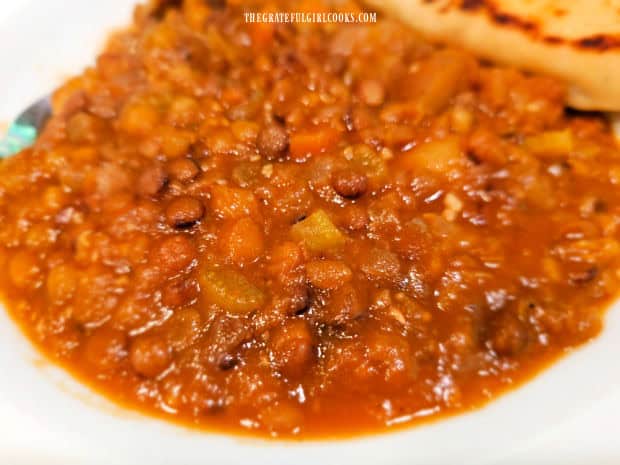 A close up photo of the lentil potato soup, served in a white bowl.