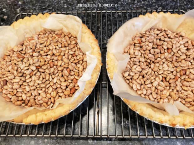 Dried beans on parchment paper are used to pre-bake the pie crusts before filling them.