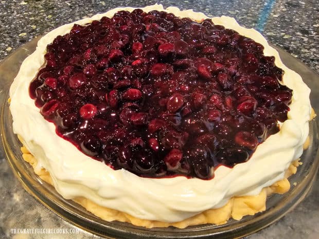 A large 10" blueberry banana cream cheese pie is covered with blueberry pie filling.