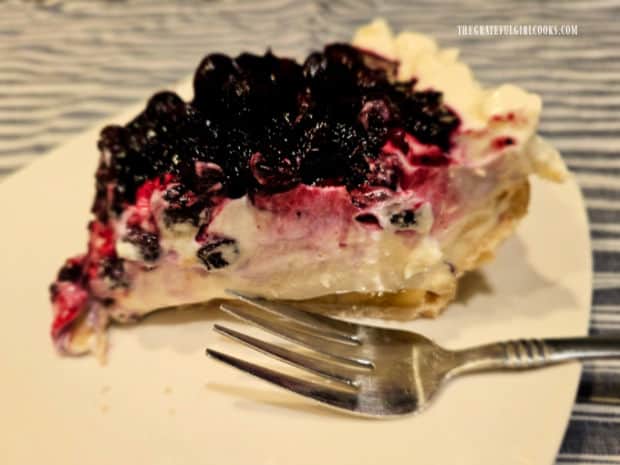 One slice of blueberry banana cream cheese pie on a white plate