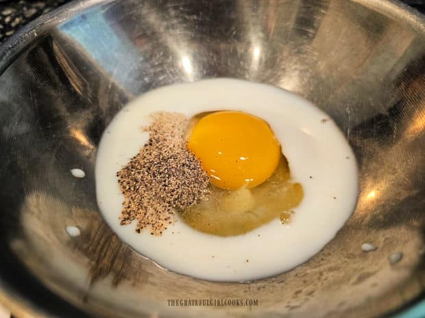 Milk, an egg, salt and pepper are combined in a medium bowl.
