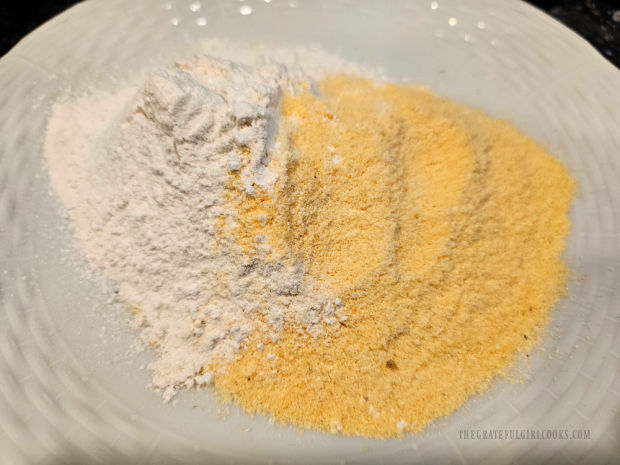 All-purpose flour and yellow cornmeal are mixed together on a white dinner plate.