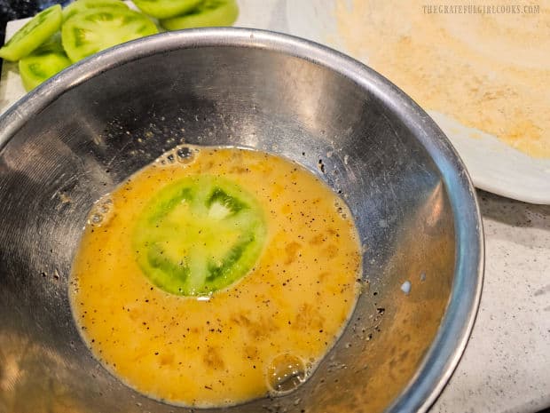 Tomato slices are coated with the egg mixture (one at a time).