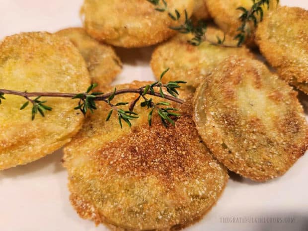 Garnished with fresh thyme leaves, the fried green tomatoes are served.