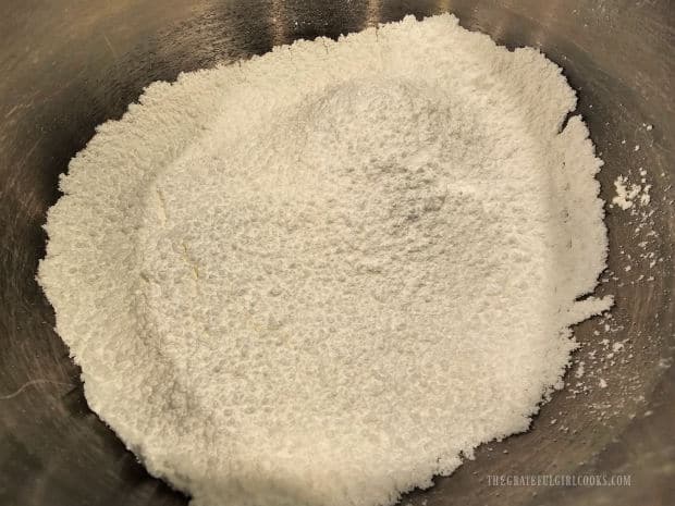 Powdered sugar is sifted into a large mixing bowl.