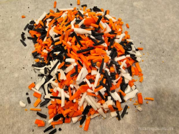 Black, orange and white homemade decorative sprinkles are combined for storage.