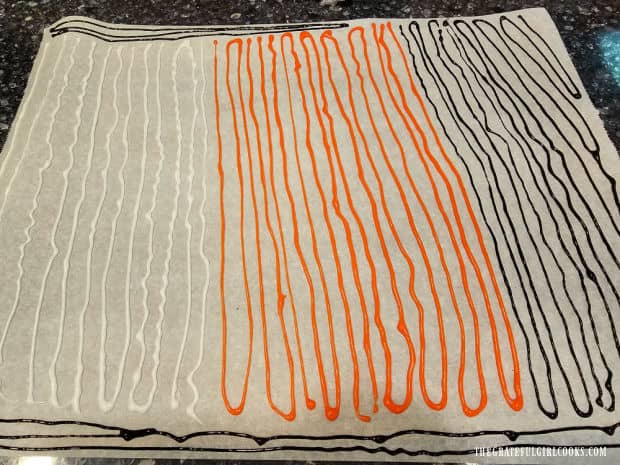 The colored icing is piped onto parchment paper in long, thin lines and dried overnight.