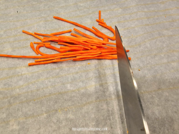 Fully dried orange icing is cut into small pieces using a sharp knife. 