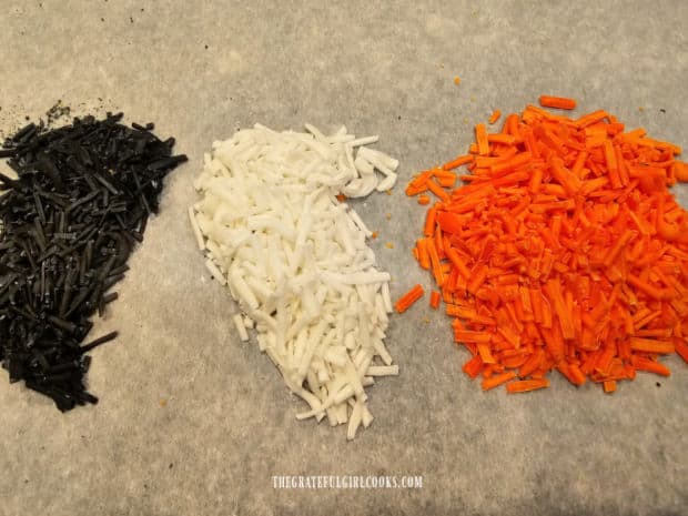 Three piles of black, white and orange homemade decorative sprinkles, ready to use.